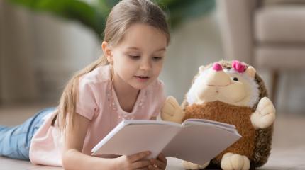 Ein Kind liest seinem Kuscheltier vor
